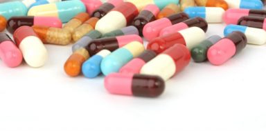 A variety of different pills, all different colors, on a white background.